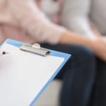 Psychotherapist writing in blank notepad at therapy session